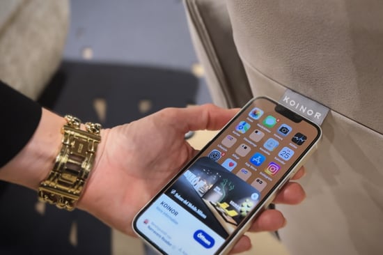 Hand mit Smartphone am NFC-Tag eines KOINOR-Polstermöbels, auf dem Display erscheint die Meldung des Digitalen Produktpasses